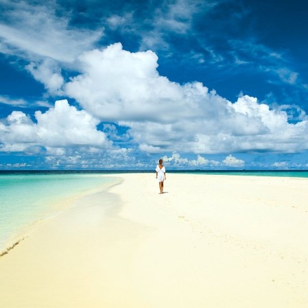 Turista che cammina lungo la spiaggia biance del bravo maayafushi alle Maldive